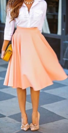 Knee-length, flared peach skirt with A-line silhouette, paired with a fitted white button-up shirt, embodying pastel outfit ideas for spring.