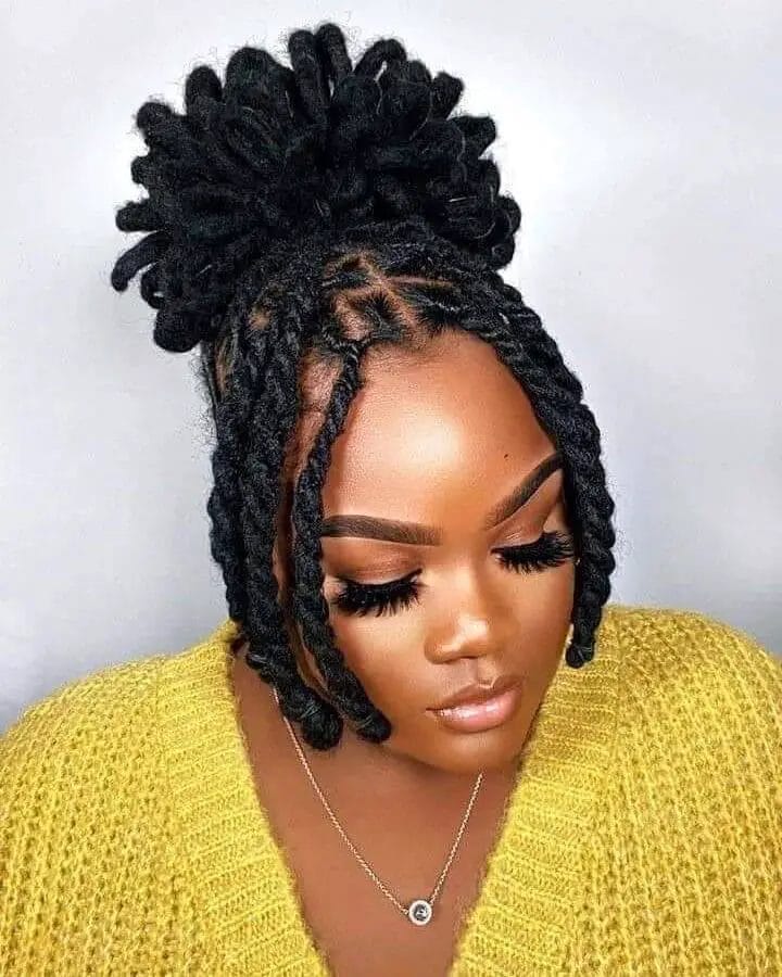 Dreadlock hairstyle with front braids leading to a voluminous bun on top.