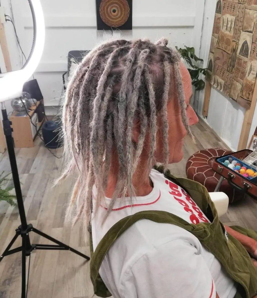Gradient of white dreadlocks transitioning from short in the front to shoulder length at the back.