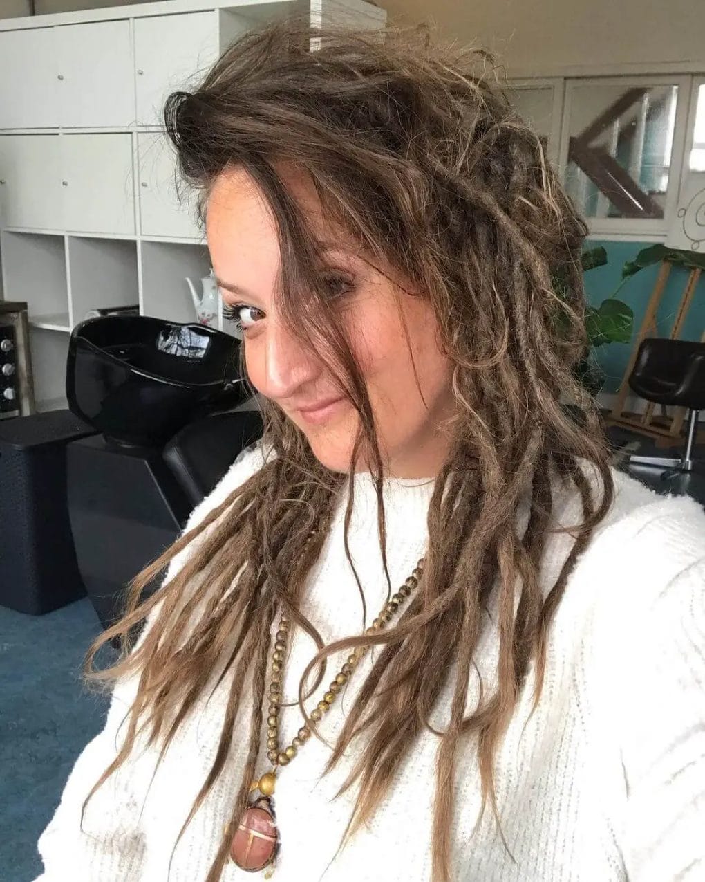 Brunette hairstyle transitioning from a smooth texture at the crown to dreadlocks towards the ends.