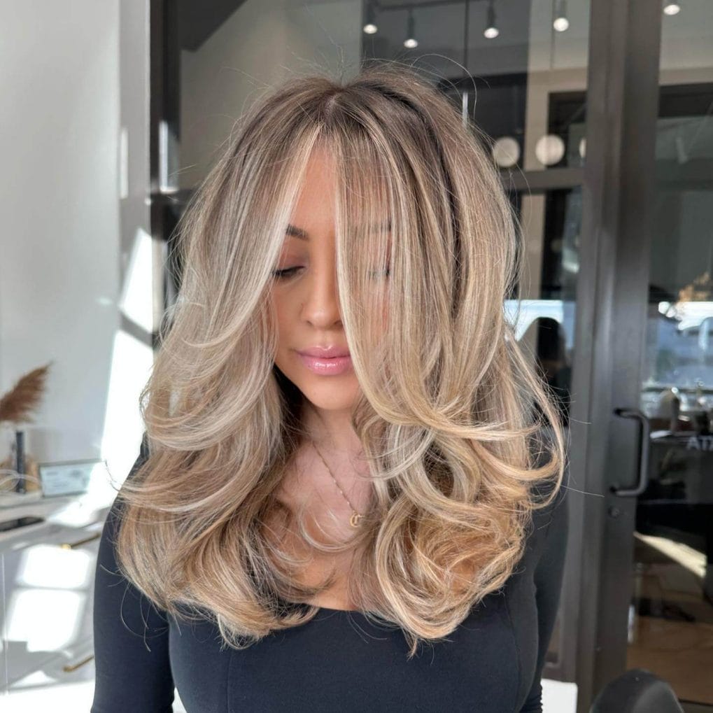 Ash blonde and caramel balayage with voluminous blowout cascading layers.