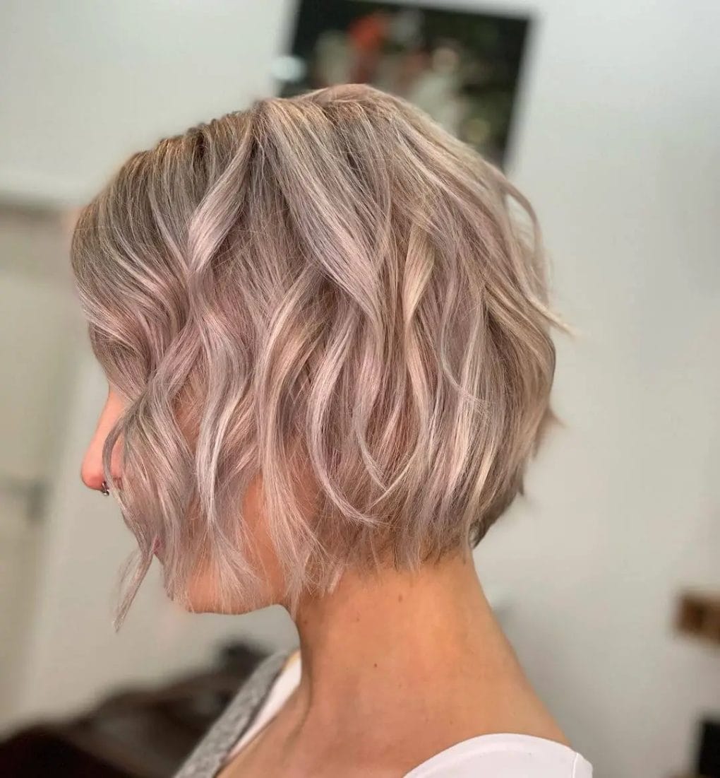 Blonde bob with pink highlights and gentle waves.