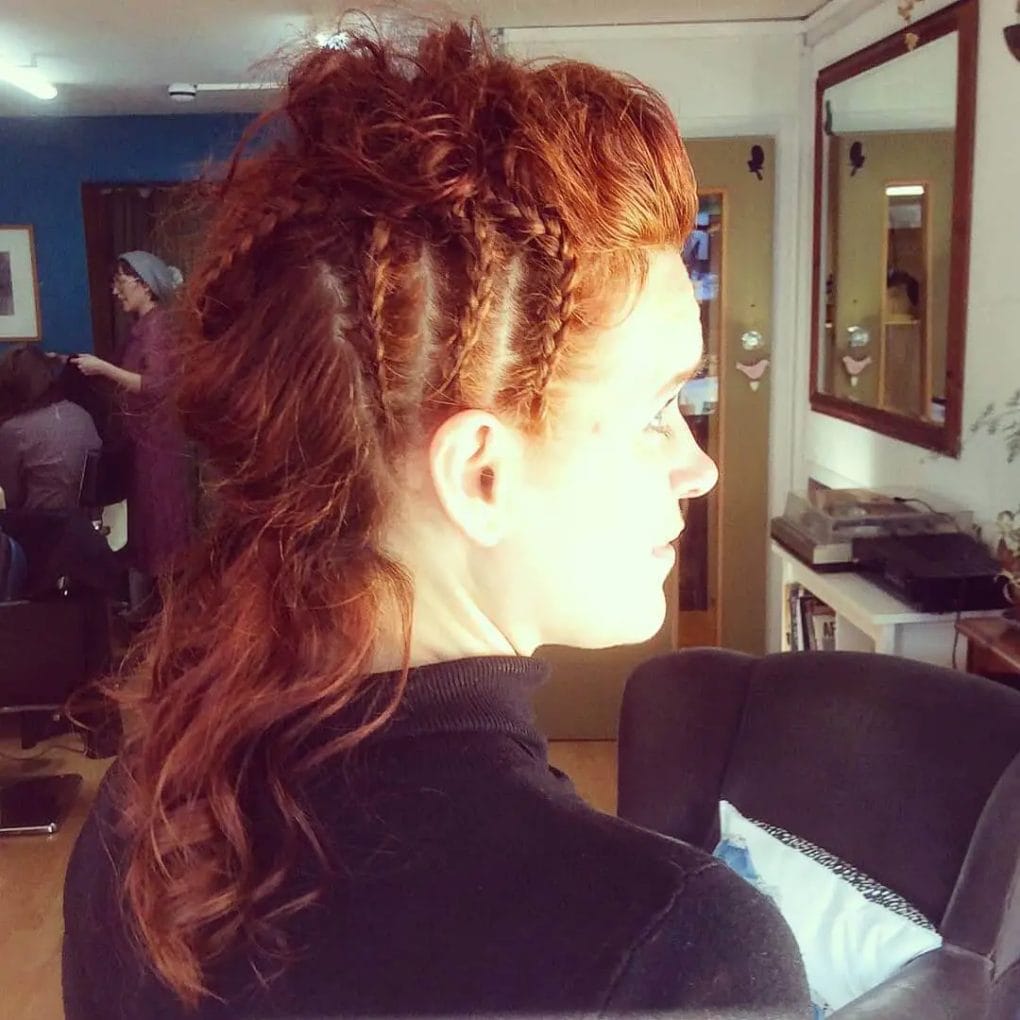 Auburn Viking braids on one side with relaxed waves in a half-up updo.
