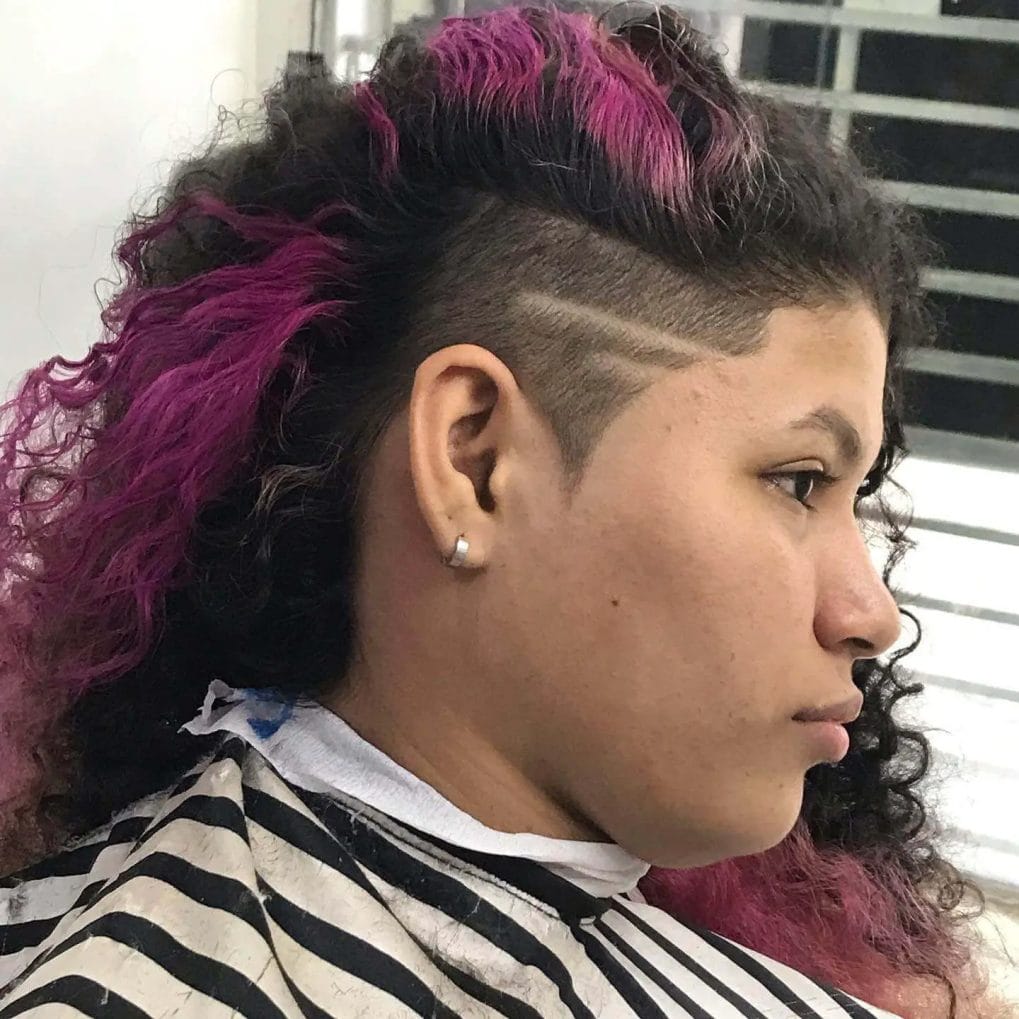 Side-swept curly top in bold magenta over a sharp geometric undercut.