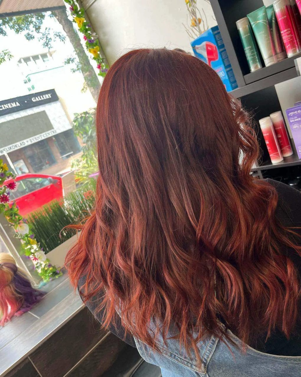 Brunette base with vibrant red balayage, soft waves, and layers.