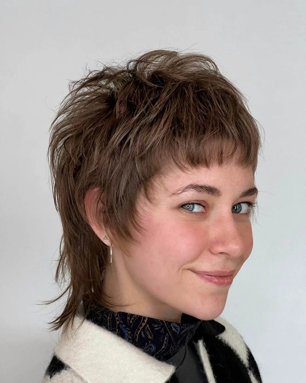 Pixie brunette wolf cut with rebellious choppy layers and subtle highlights.