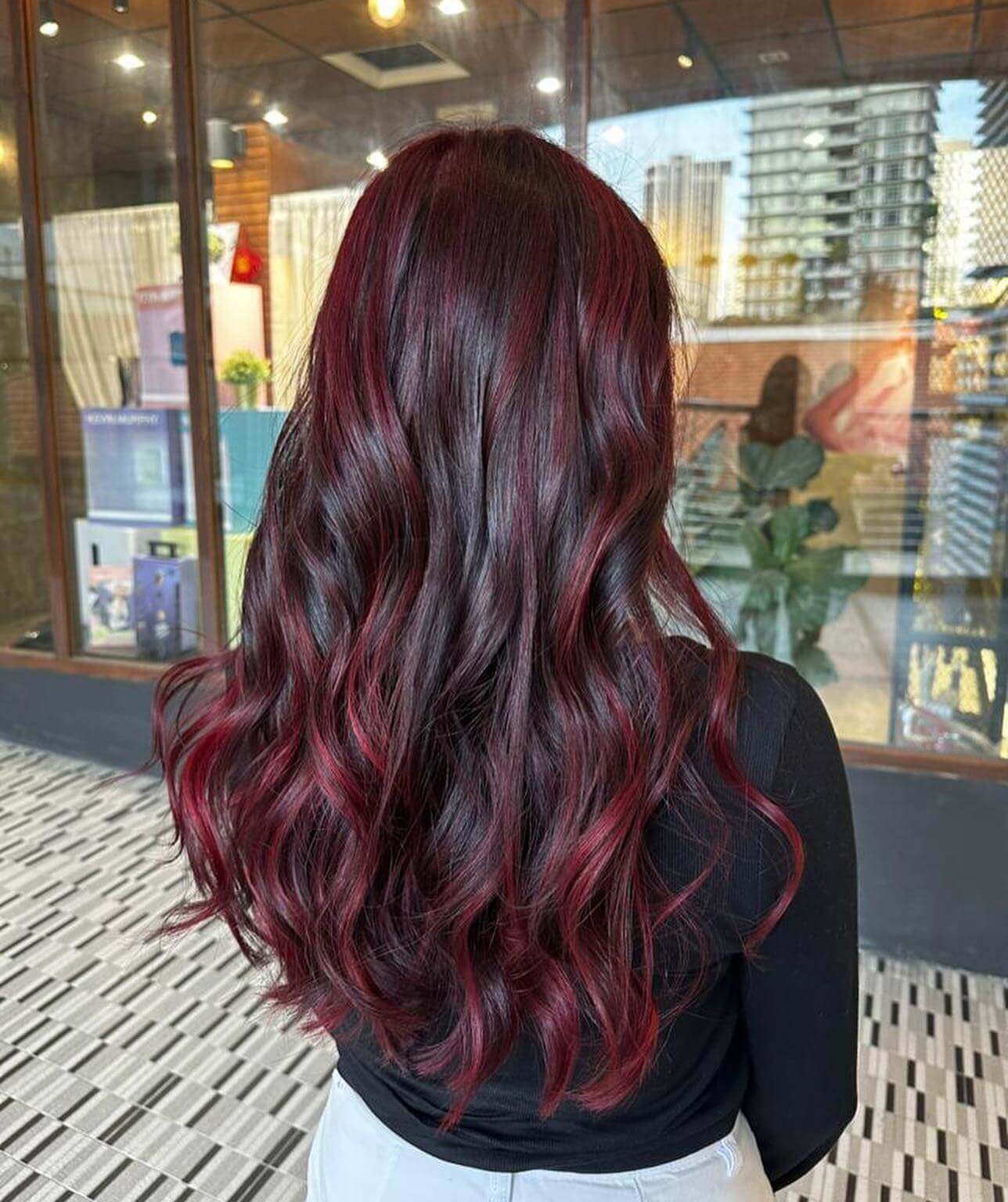 Deep burgundy and crimson balayage on brunette, layered waves.