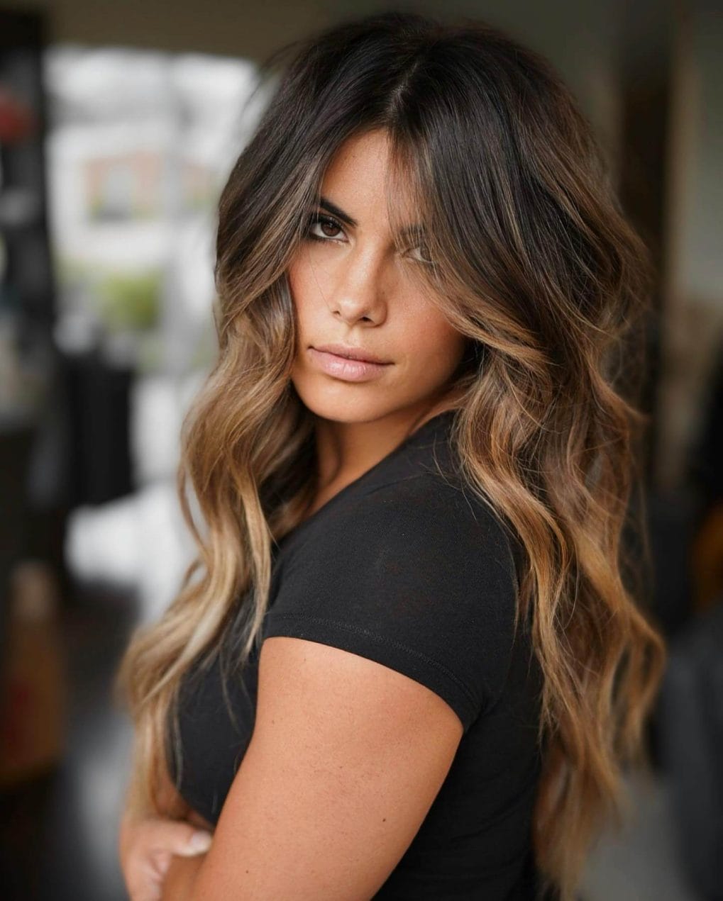 Bold balayage from dark roots to caramel blonde, soft wavy layers.