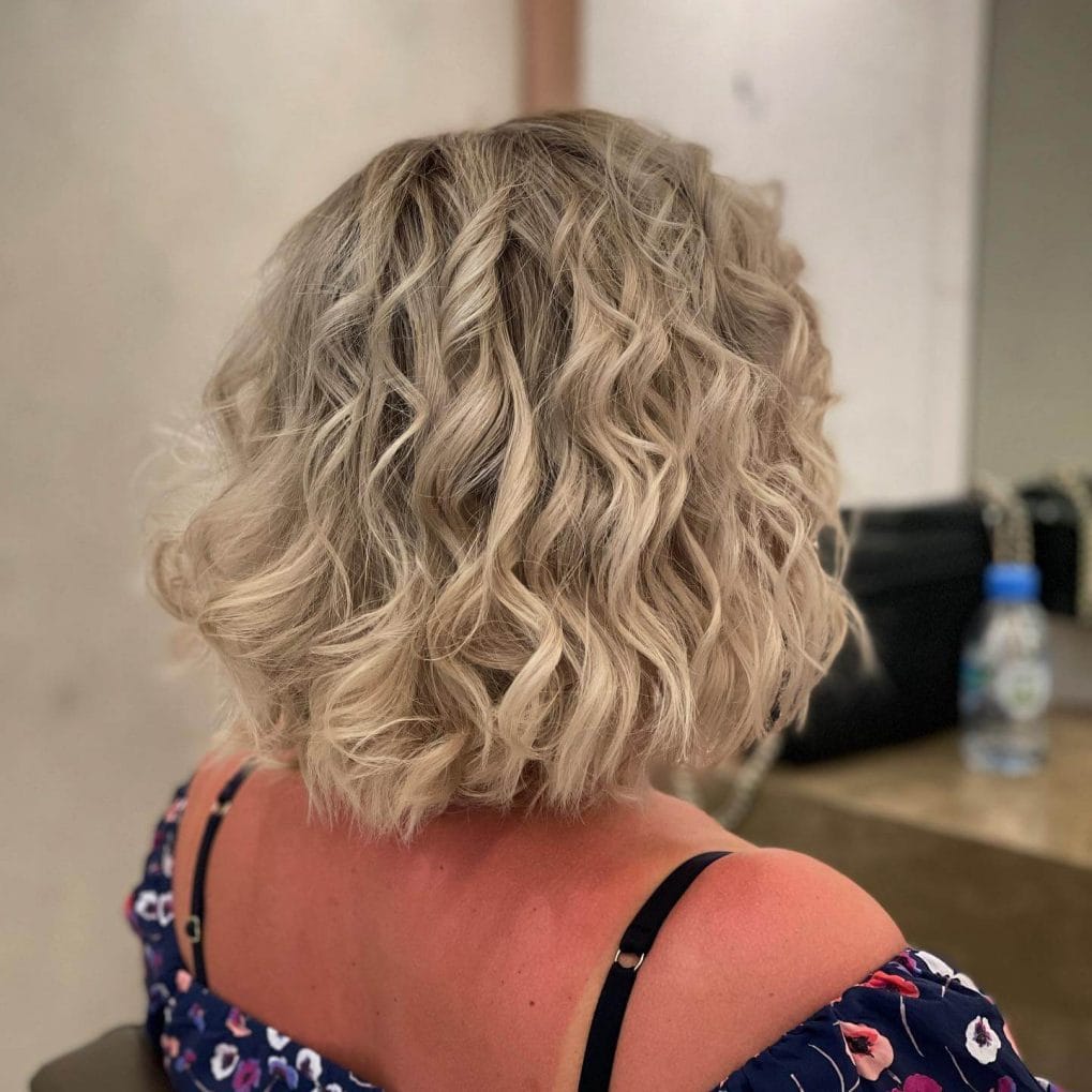 Cascading platinum blonde curls in Italian bob.