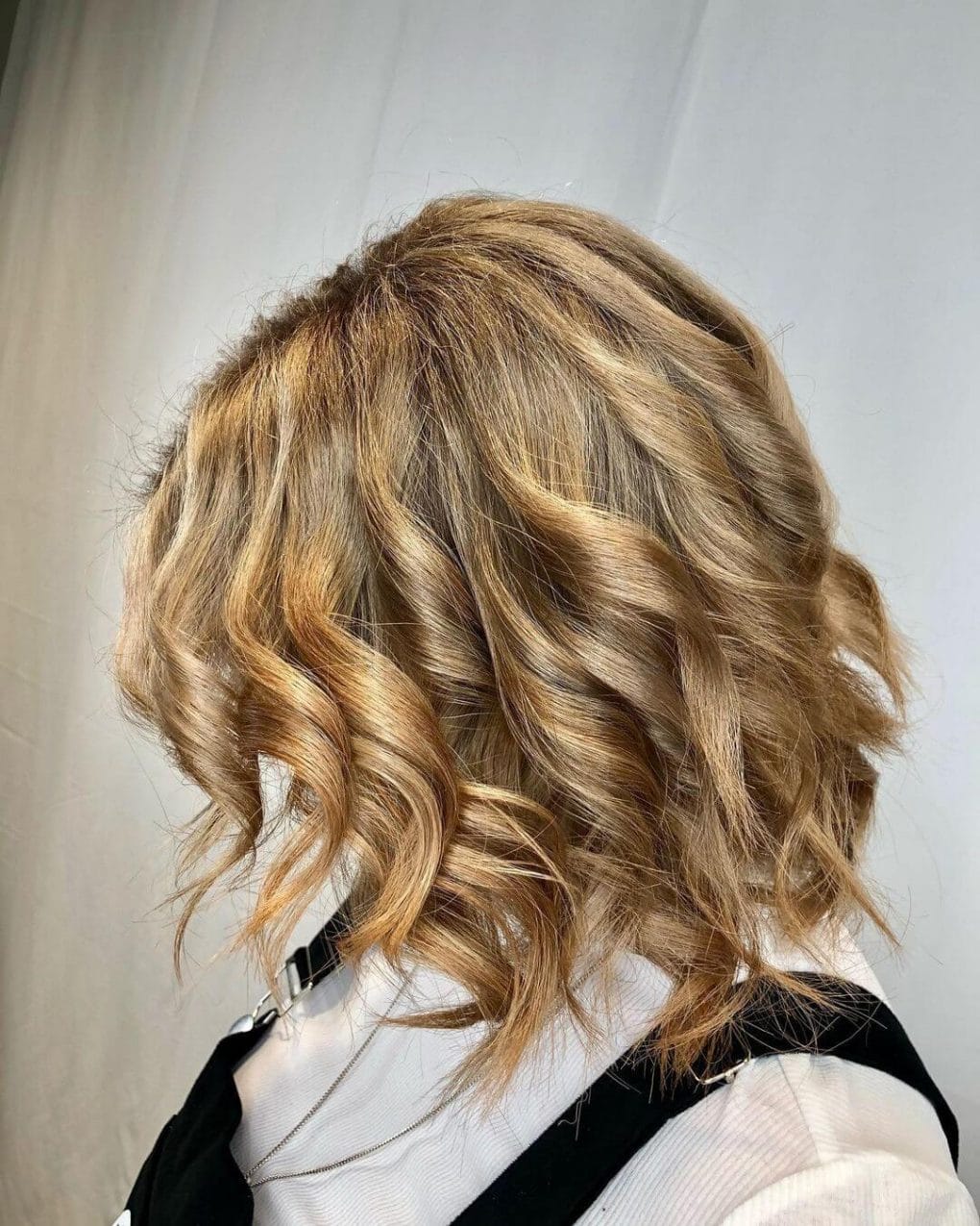 Tousled wavy bob in warm blonde tones.