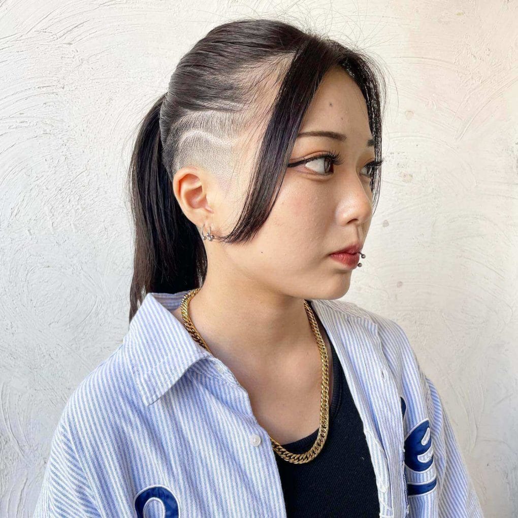 A smooth, black ponytail with a side undercut featuring an elegant wave design.