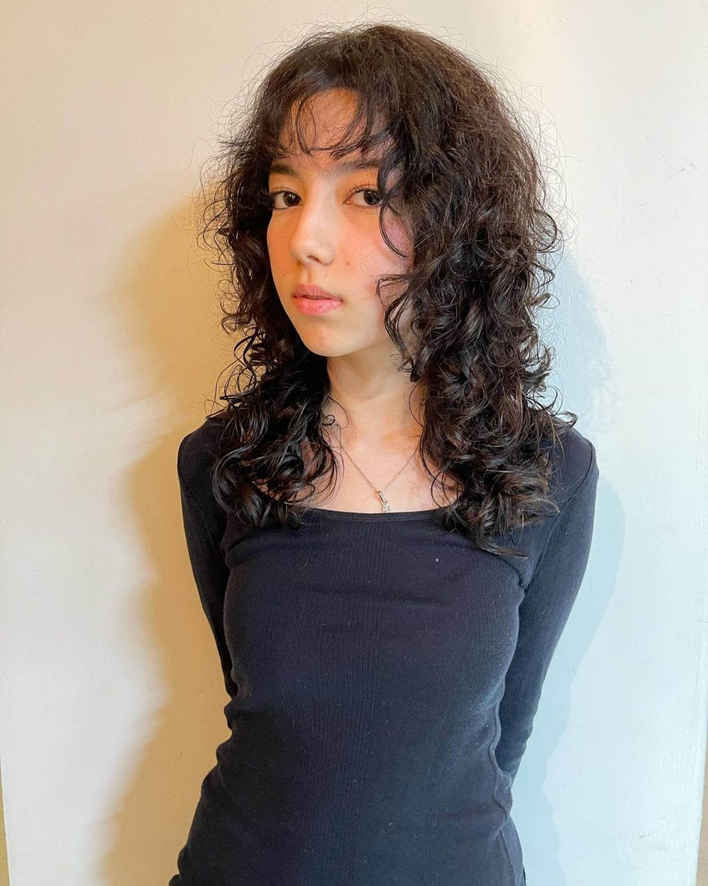 Curly espresso wolf cut with volumizing layers and tousled fringe.