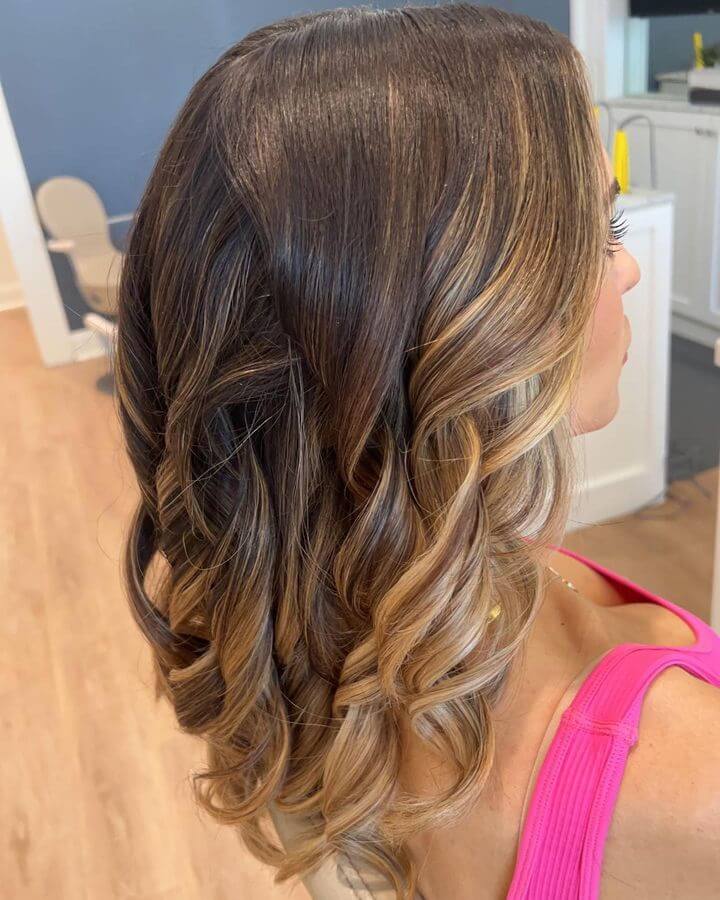 Dark to honey caramel balayage, voluminous curls blowout and layered cut.