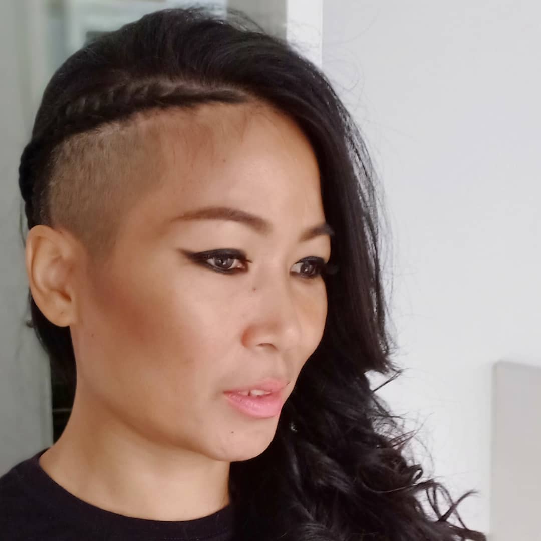 Asymmetrical hairstyle with one side of voluminous curls and a sleek side undercut.