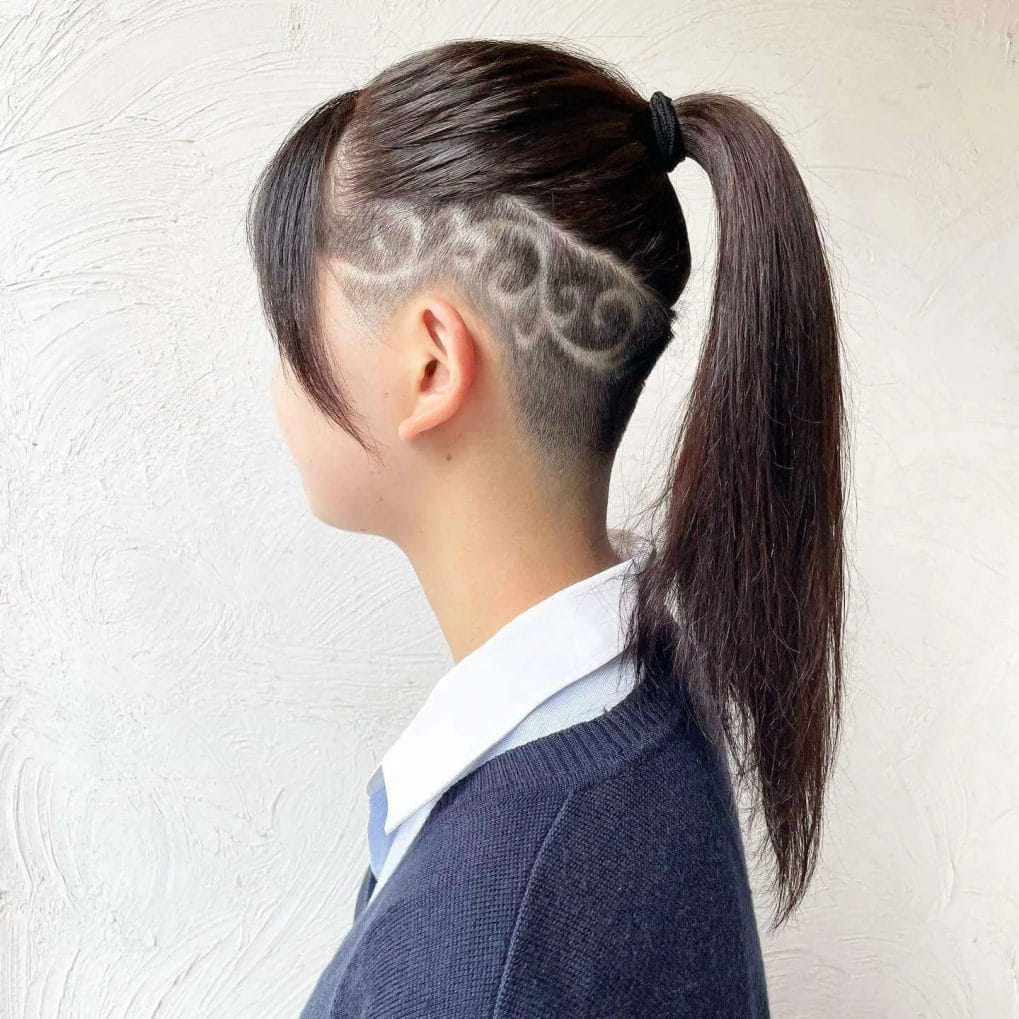 A sleek, long ponytail with an artistic, flower-like undercut pattern on the sides in rich chocolate brown hair.