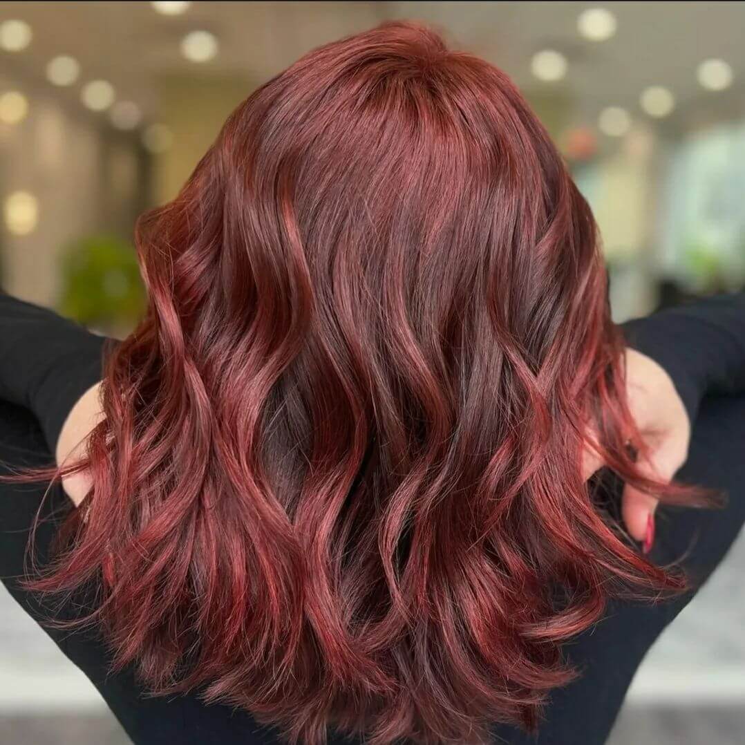 Fiery red balayage on mid-length cascading layers, brunette base.