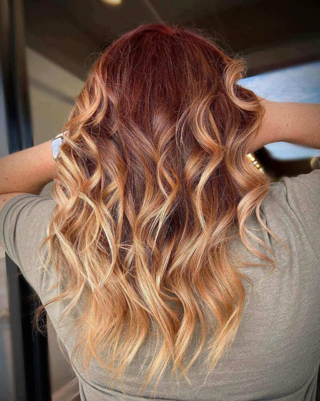 Rich red roots blending into golden blonde on textured waves.