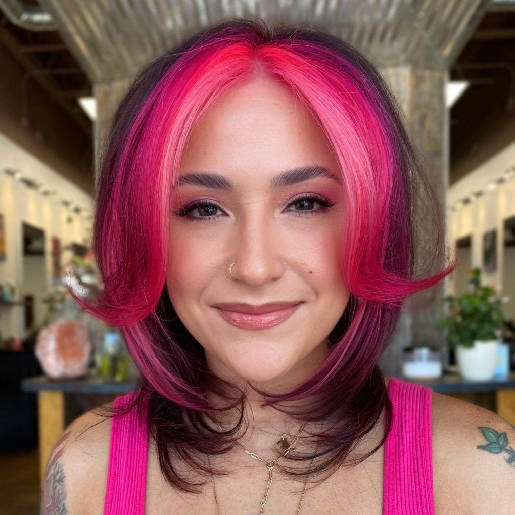 Bold fuchsia bob with darker root fade and soft curls.