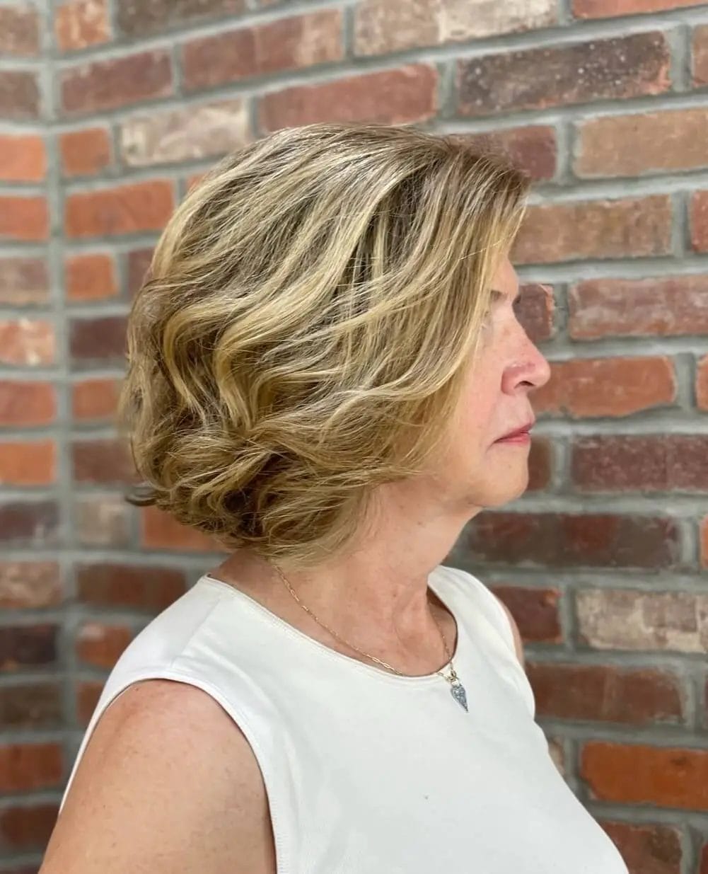 Layered bob with curls and honey ash highlights for an elegant look.