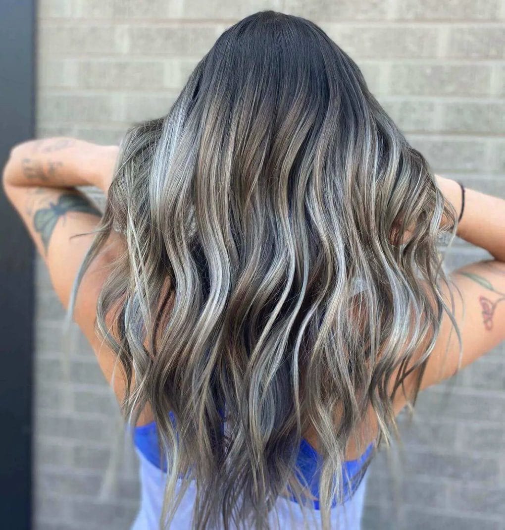 Long layers with gray highlights and a sun-kissed balayage effect.