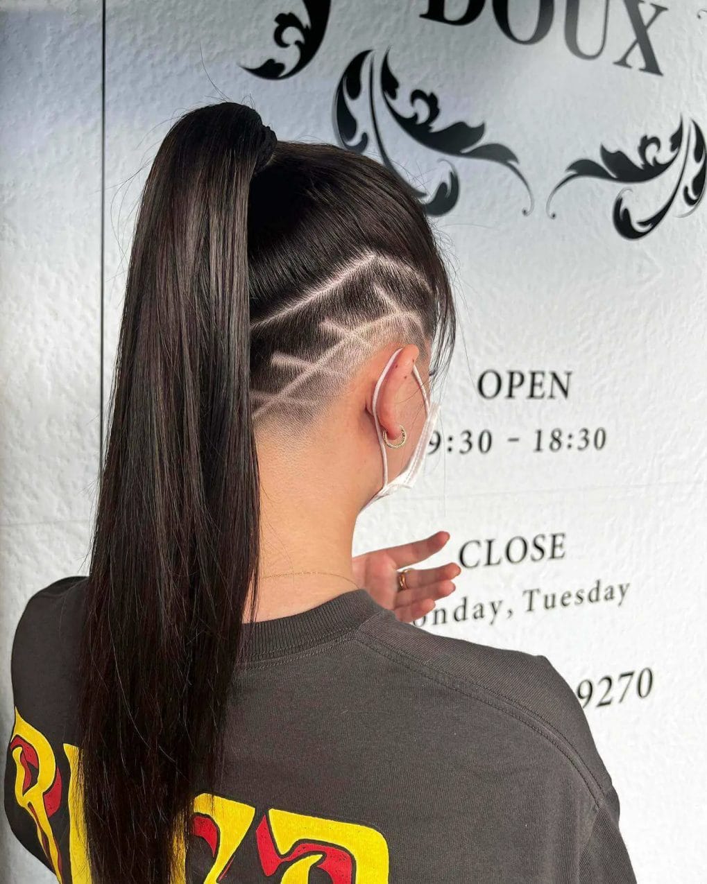A smooth high ponytail with a neatly designed line pattern undercut.