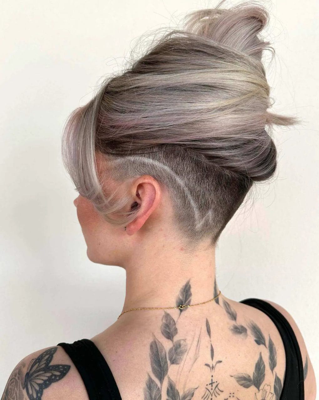 A voluminous top bun in cool-toned silver and lavender balayage, with an undercut beneath.