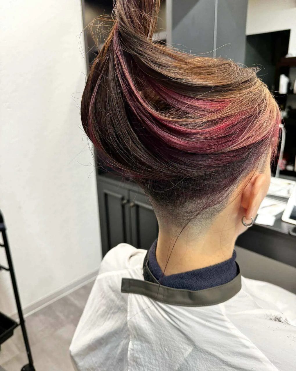 Long hair blending deep brown to burgundy balayage, with a subtle undercut.