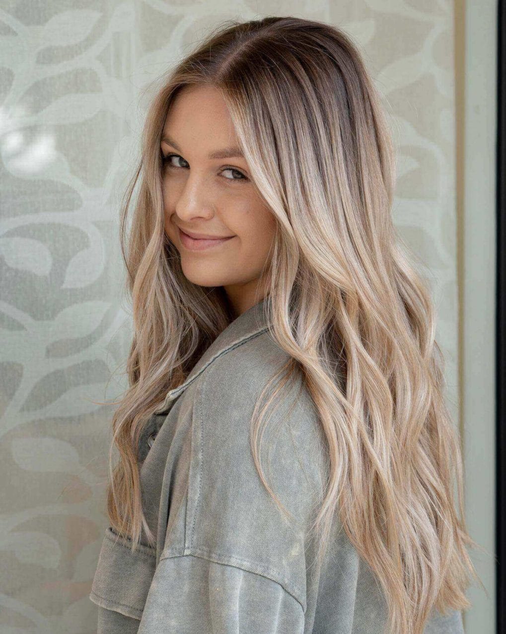 Long layers with soft waves, balayage blending cool ash base into platinum blonde tips