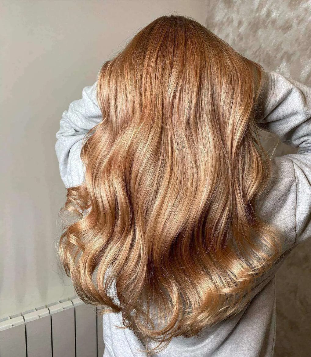 Luxurious waves in a blonde and soft red balayage gradient.