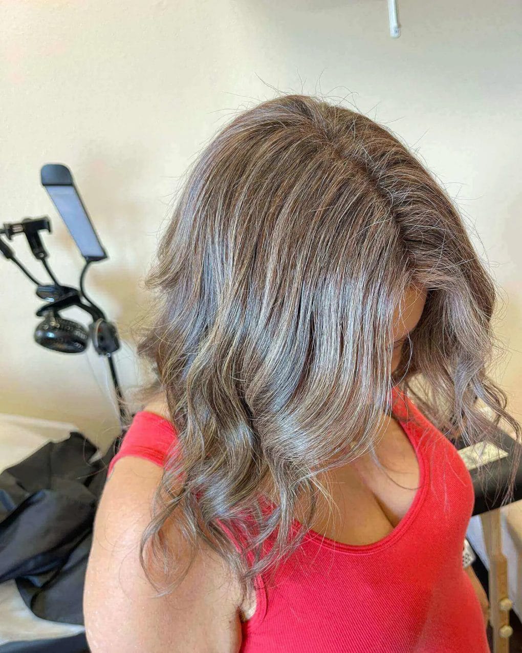 Medium-length hair with voluminous waves and gray-ash blonde highlights.