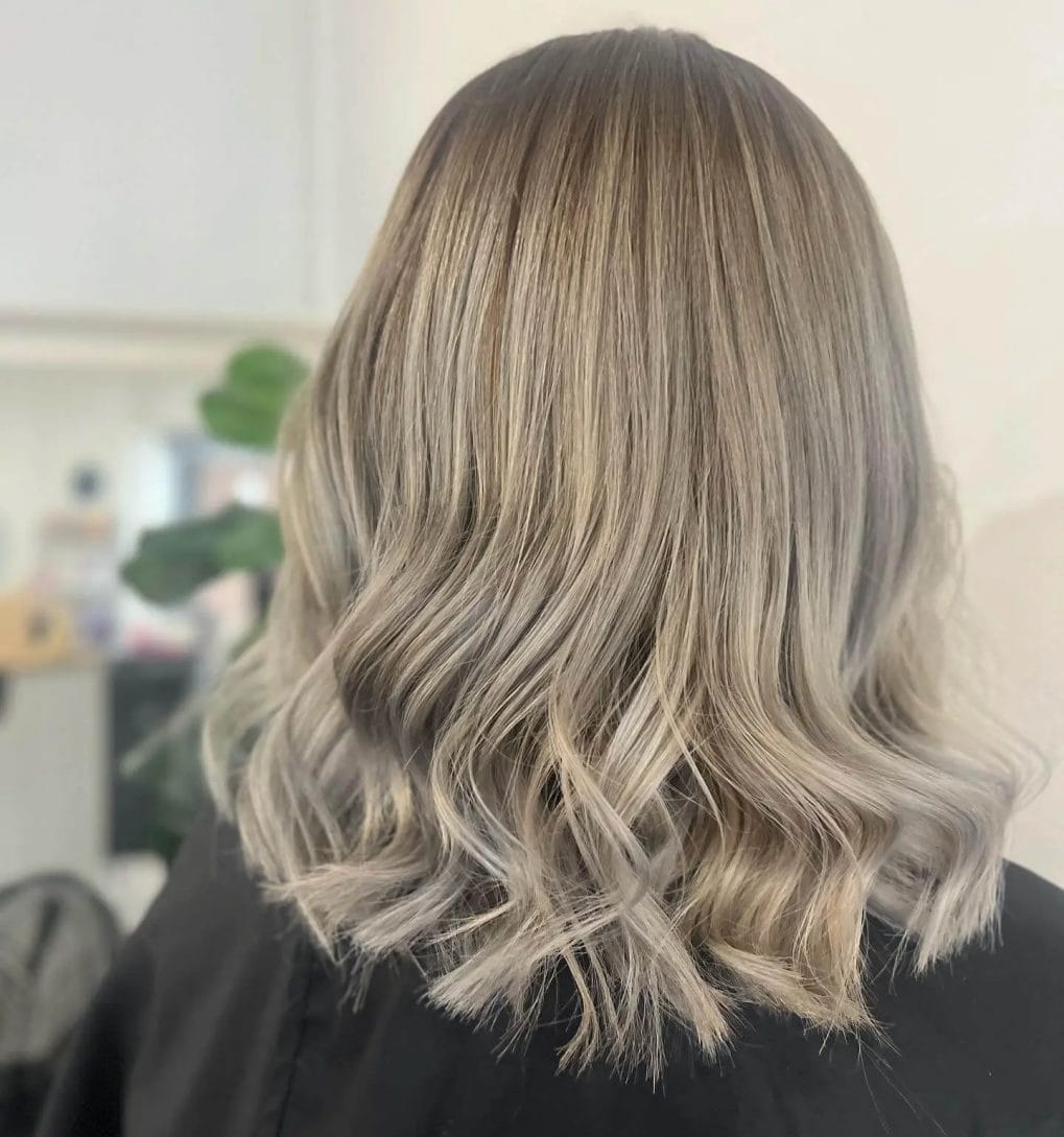 Mid-length cut, flowing layers, ash to icy blonde fade.