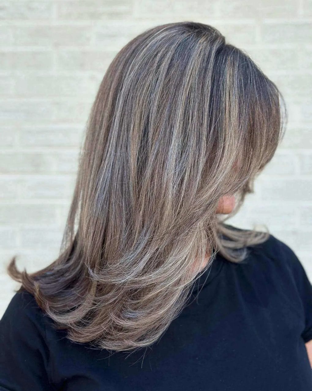 Elegant mid-length cut with long layers and volumizing silver ash highlights.