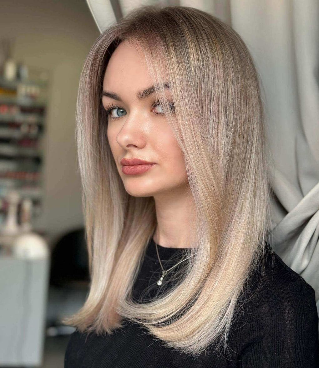 Straight mid-length cut with balayage from dark roots to platinum blonde, creating a sharp look