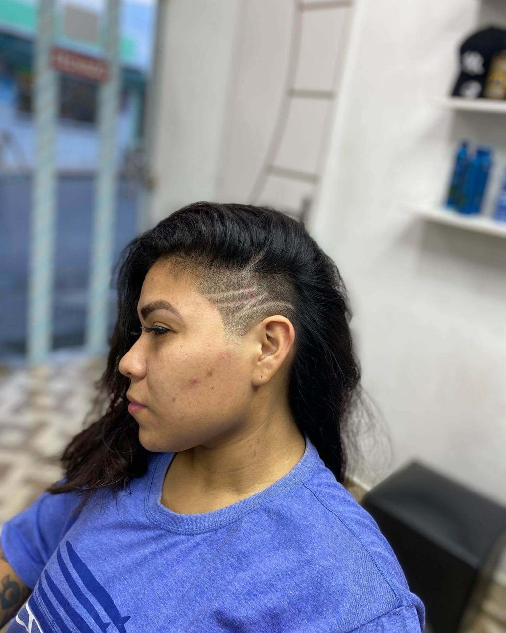Long hair swept back, showcasing a geometric undercut on the side.