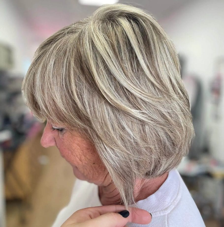 Grey and blonde modern bob with voluminous layers and side sweep.