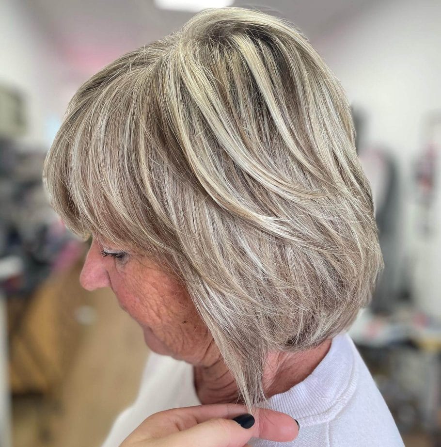 Grey and blonde modern bob with voluminous layers and side sweep.