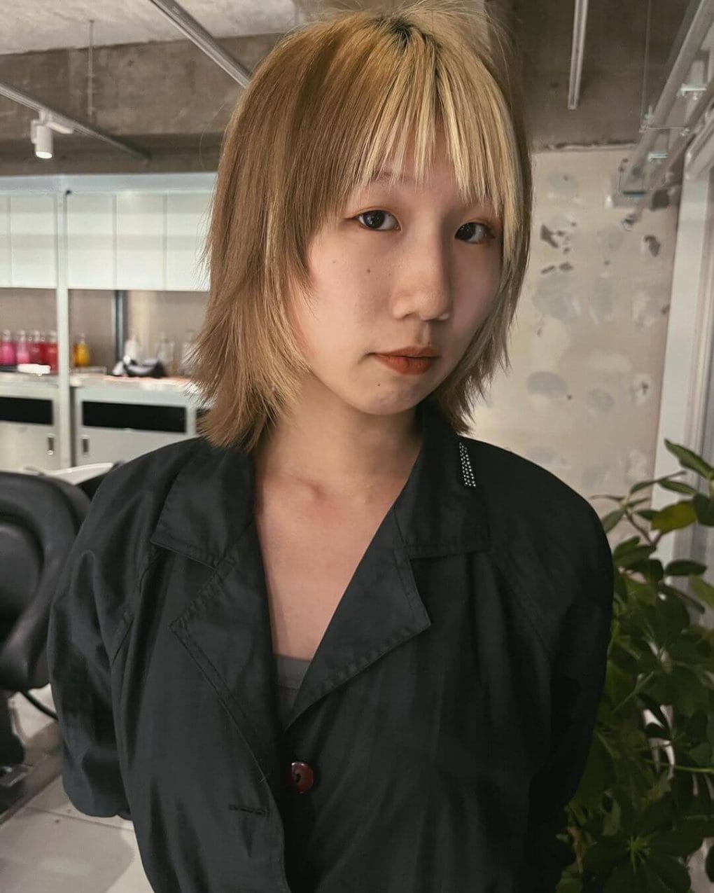 Muted blonde shaggy wolf cut with choppy fringe and dark roots.