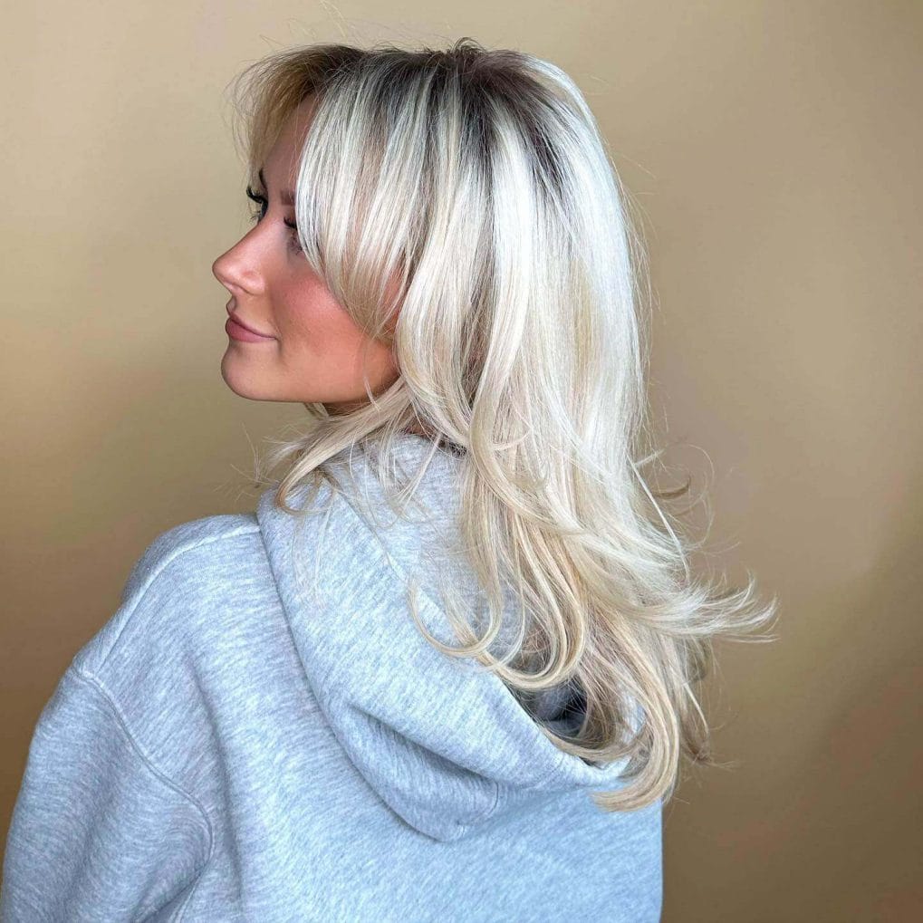 Bright platinum blonde with darker roots, elegant long layers.