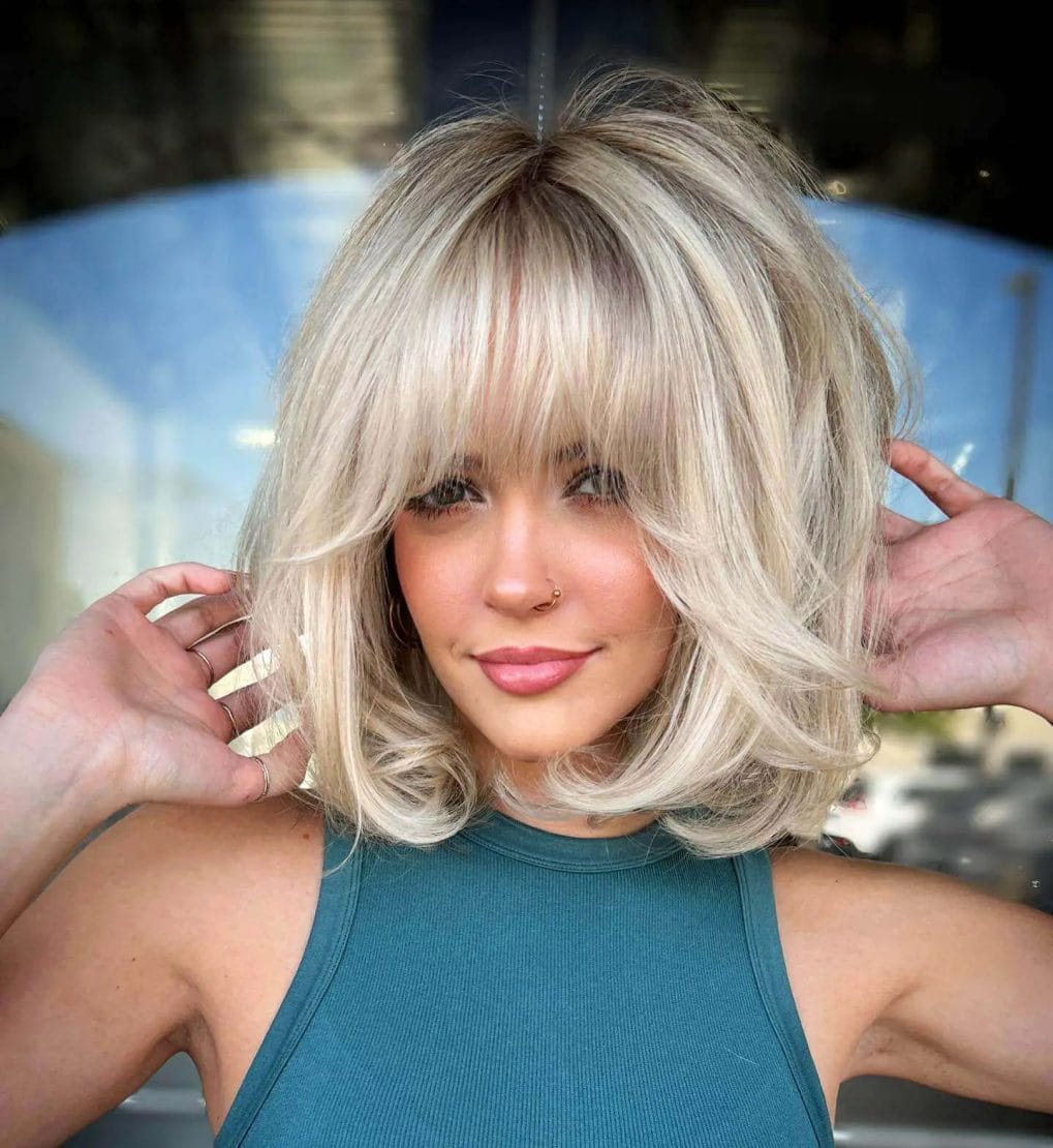 Playful blonde bob with full fringe, bouncy blowout style.