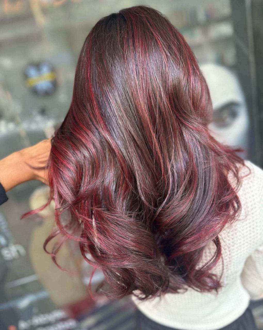 Flowing long layers with red balayage on brunette.