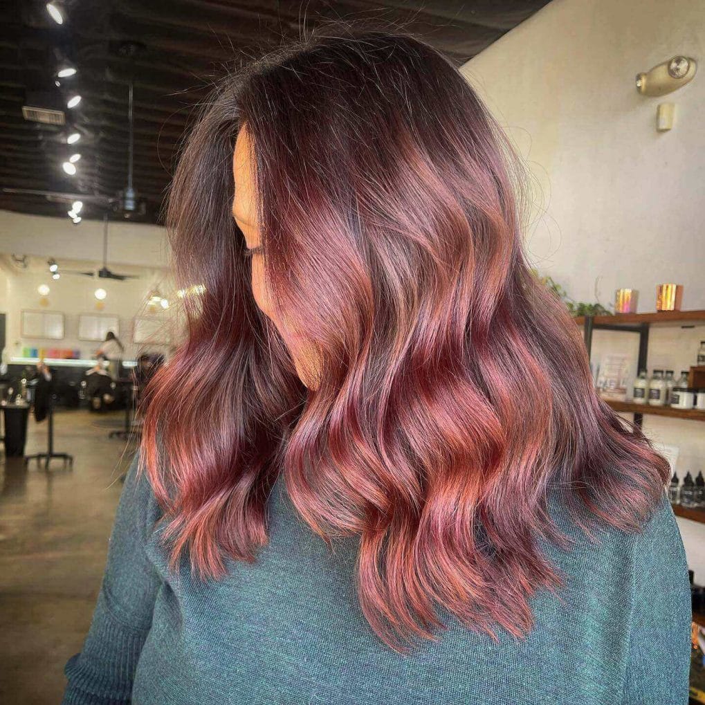 Rose gold balayage on brunette, shoulder-length with waves.