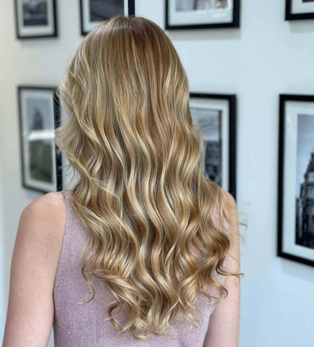 Sandy blonde balayage in waves, with seamless layers adding volume and movement, no fringe