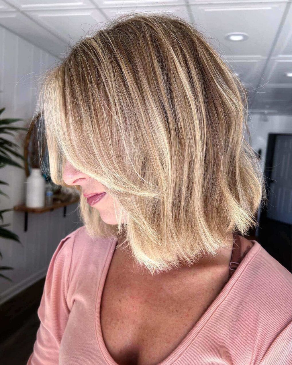 Bob with blonde balayage, styled in straight strands with subtle layers and a side-swept fringe