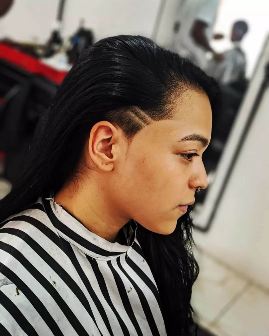 Side-swept black hair revealing a geometric-patterned undercut when tucked behind the ear.