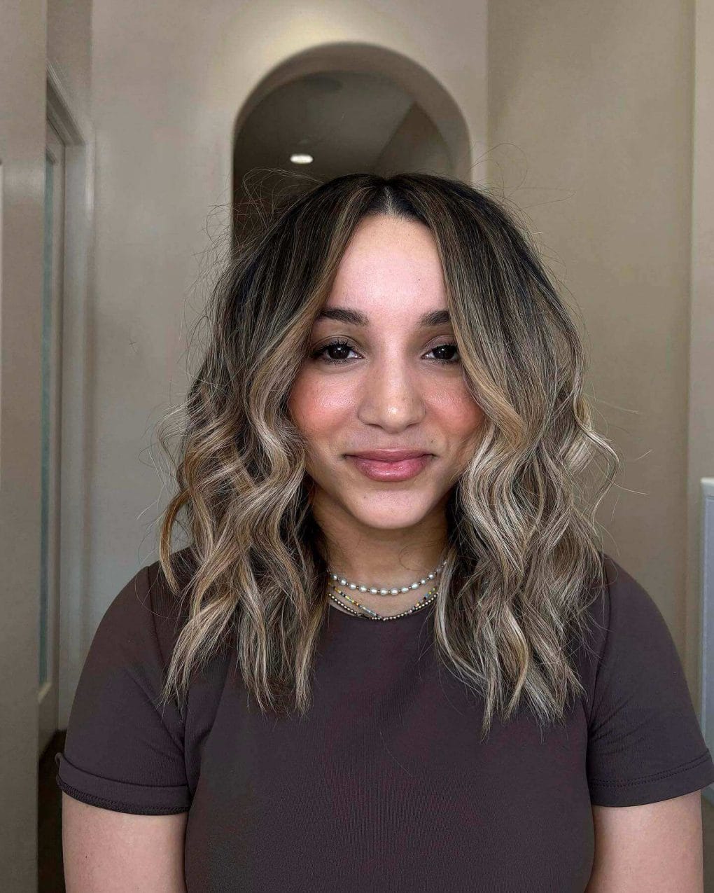 Mid-length cut with sun-kissed balayage, styled in textured layers and loose waves