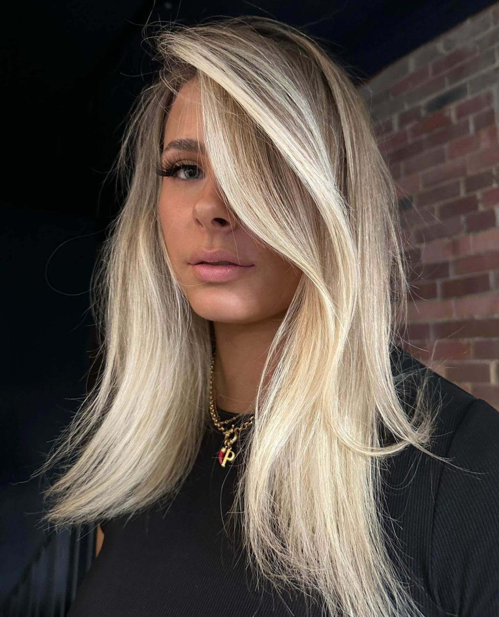 Blowout sun-kissed blonde with dark roots, effortless layered look.
