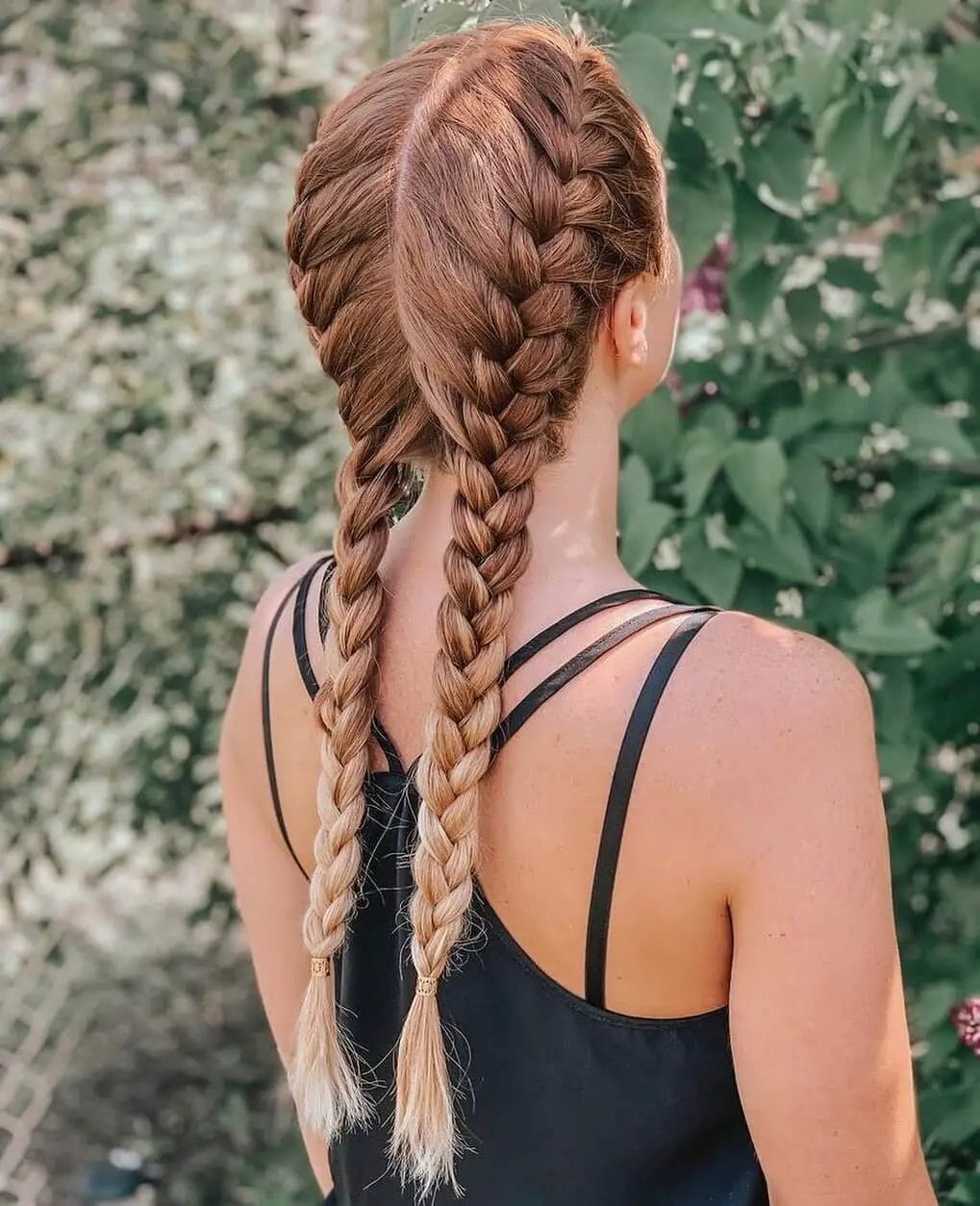 Symmetrical French braids with precision weave and blond ombrÃ© ends.
