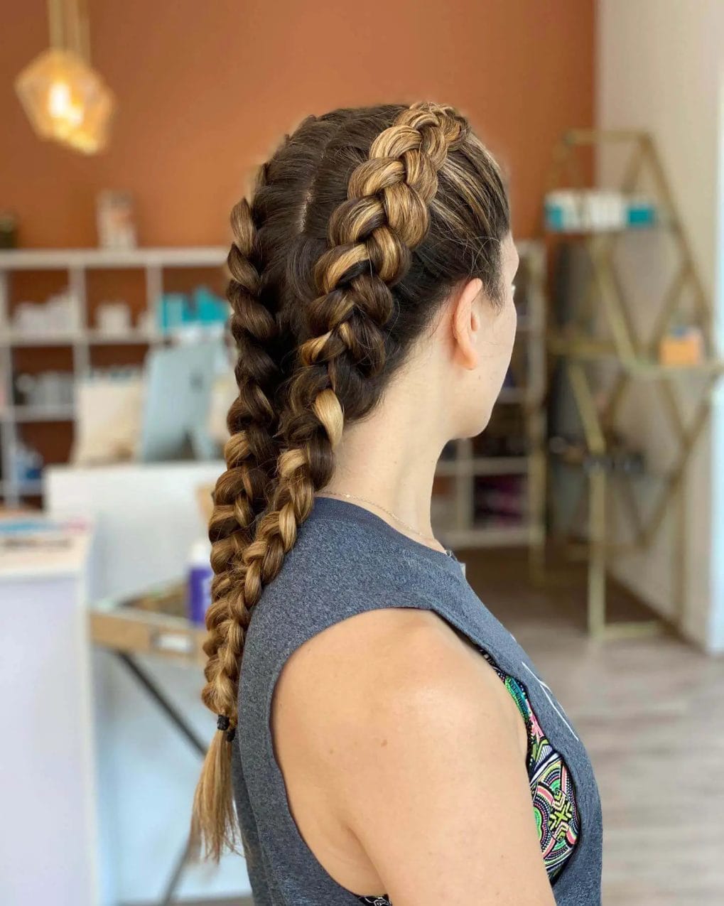 Symmetrical separate top-to-back French braids in natural brunette with golden highlights.