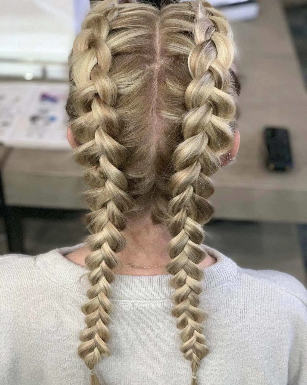Symmetrical twin French braids with honeyed blond highlights.
