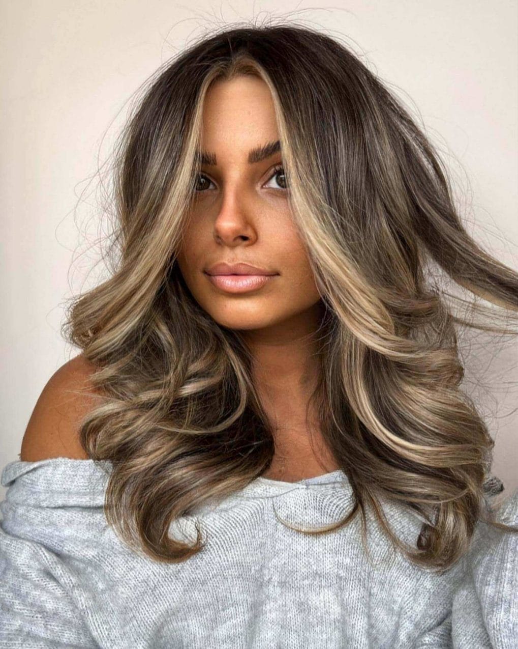 High-contrast balayage with deep roots and vanilla blonde ends, styled in voluminous layers